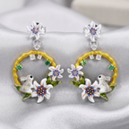 Pair of earrings with floral and rabbit design on a gray background