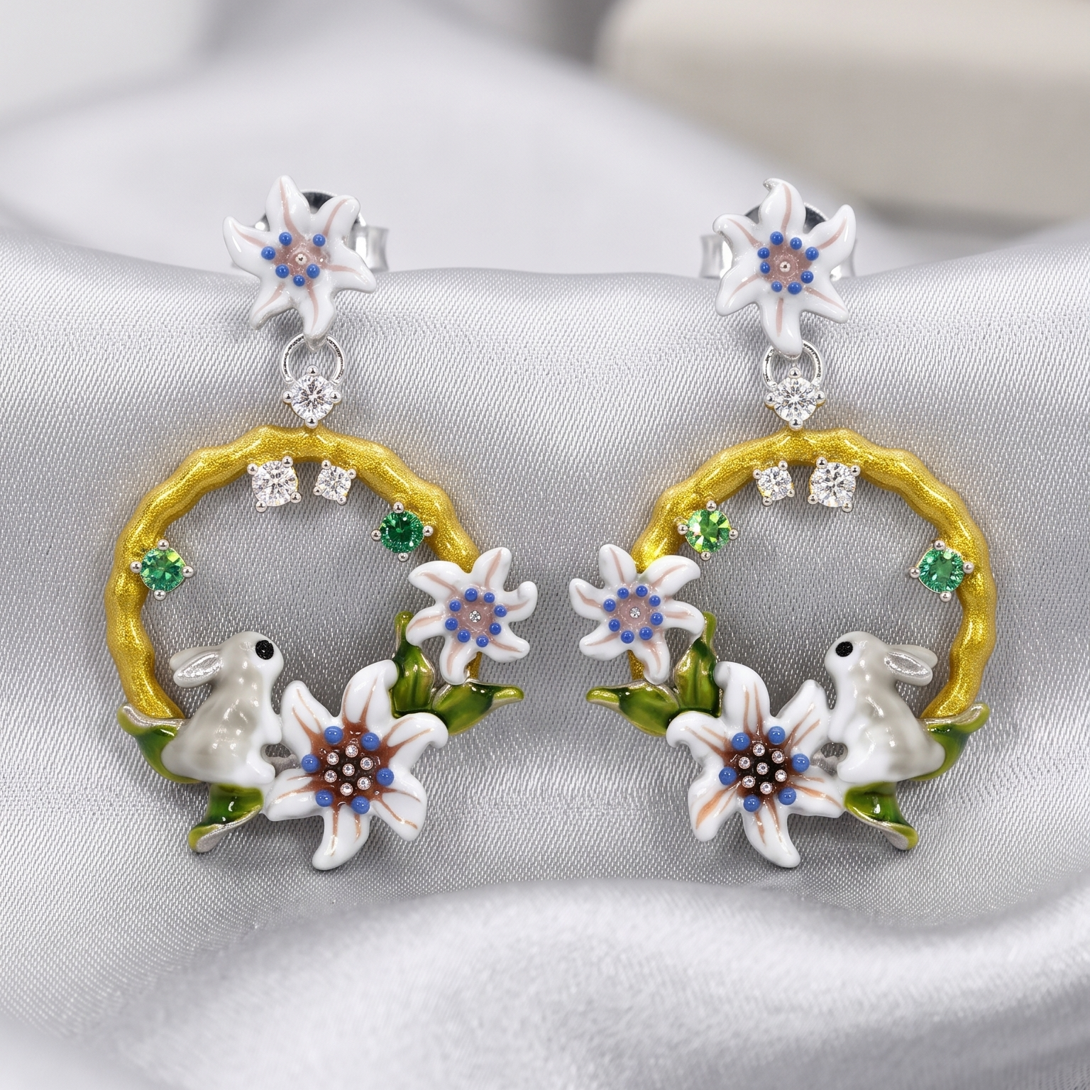 Pair of earrings with floral and rabbit design on a gray background