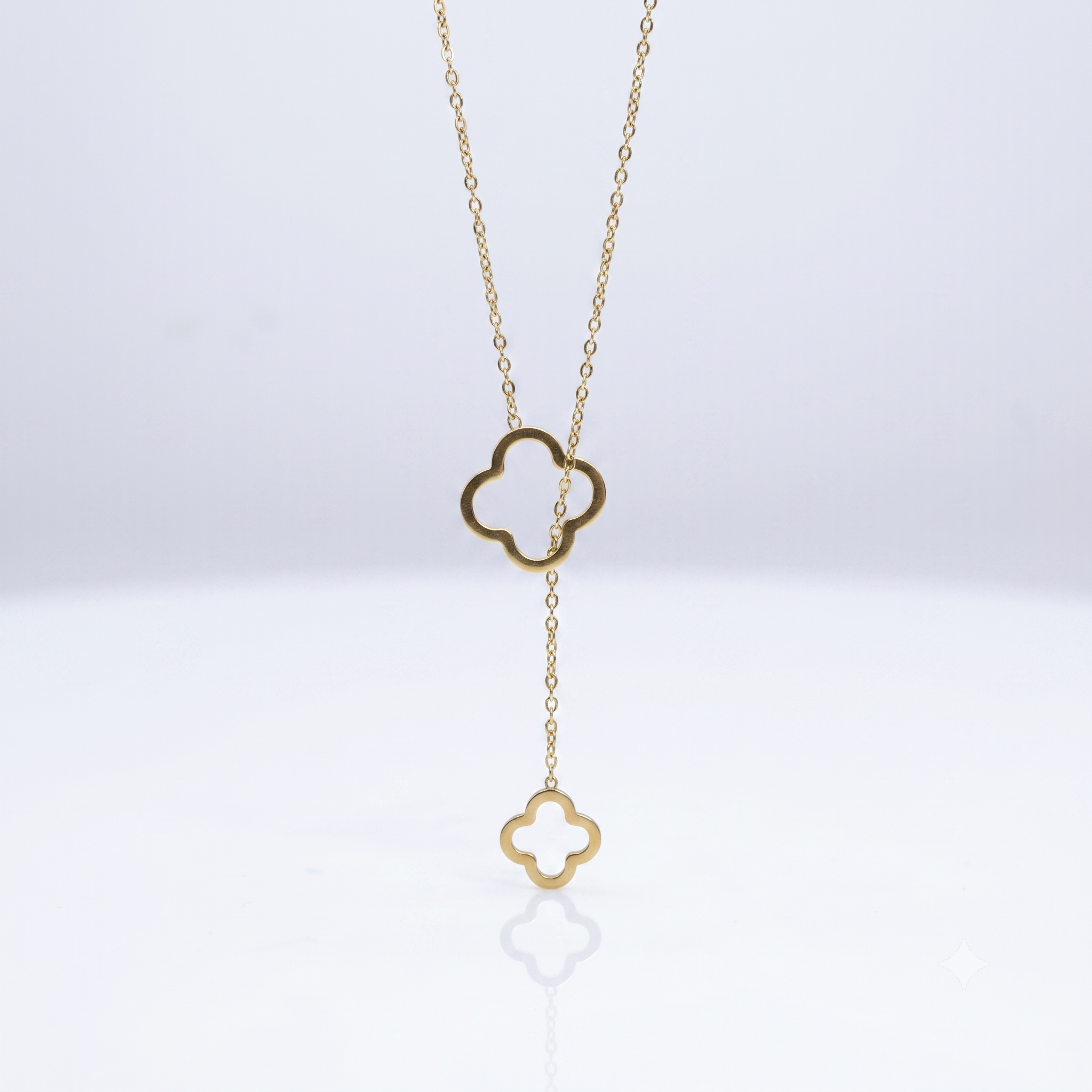 Gold necklace with clover-shaped pendant on a white background