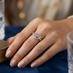 Hand wearing a silver ring with a diamond on a blue surface
