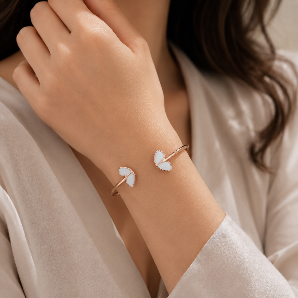 A close-up lifestyle shot of a model wearing a delicate open cuff bracelet with two white butterfly-shaped charms on a rose gold band.