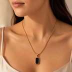 Gold necklace with a black pendant on a girl