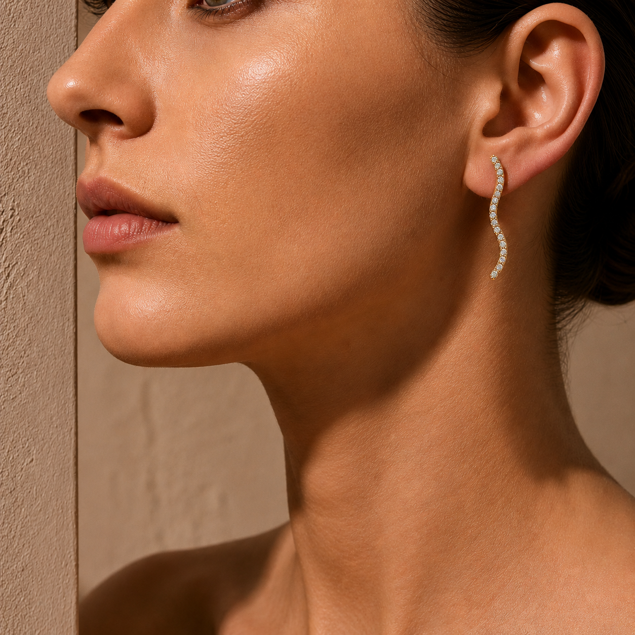 Close-up of a woman wearing a diamond earring against a neutral background