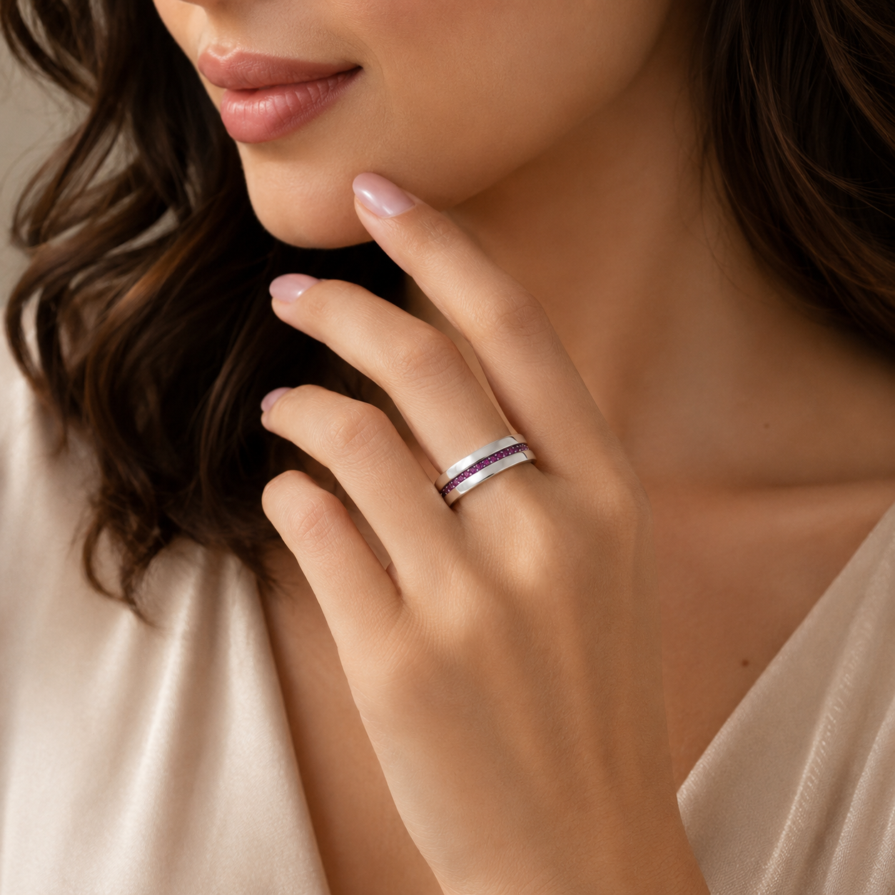 A close-up lifestyle shot of a woman wearing a slim silver band ring with a double row of small purple gemstones, shown on her ring finger.