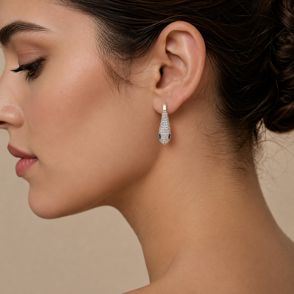 woman wearing snake rose gold earrings with diamonds and blue stone eyes