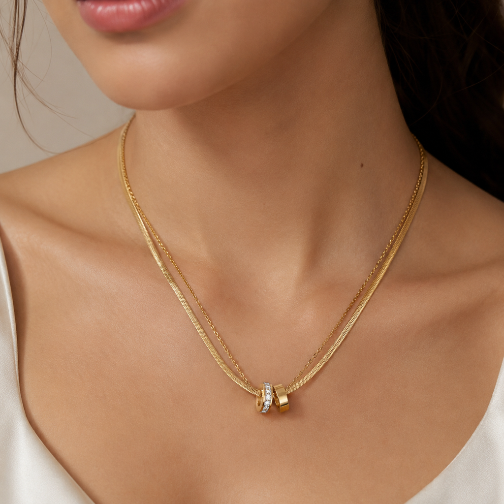 Gold necklace with a pendant on a person's neck against a neutral background