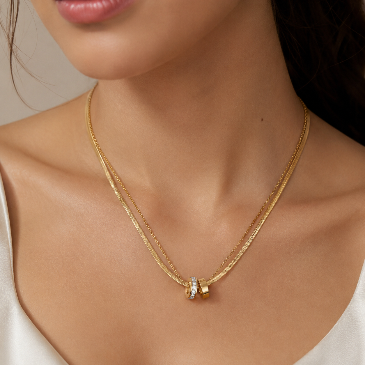 Gold necklace with a pendant on a person's neck against a neutral background